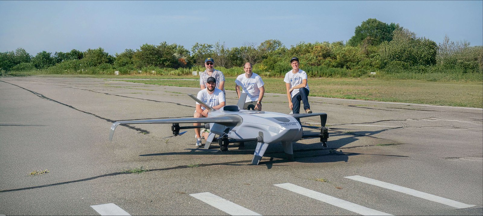 Four Unmanned United engineers with the Overwatch-LR airframe on a runway during flight testing